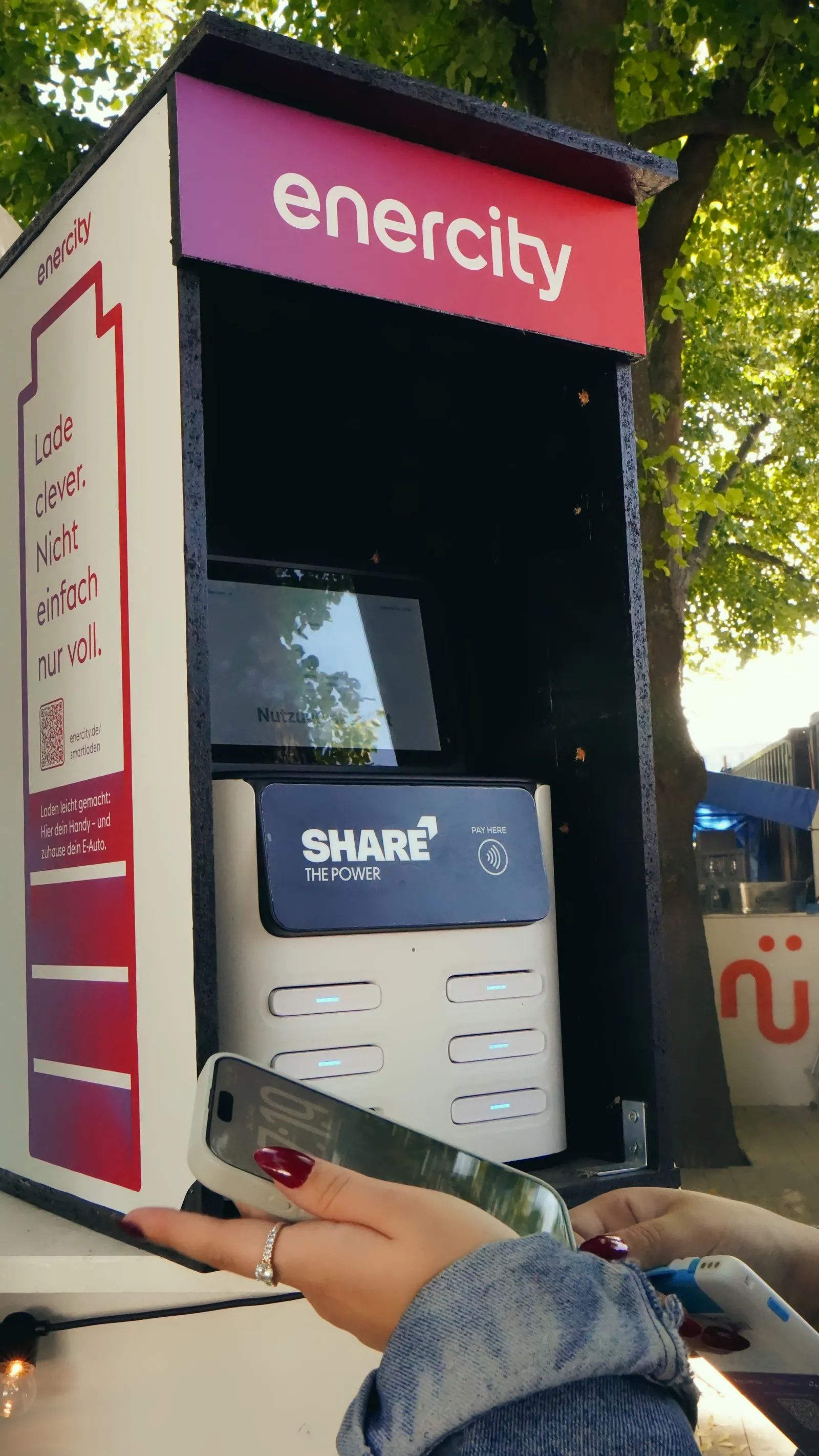 Ein junger Mann leiht eine Powerbank an einer großen SHARE Station